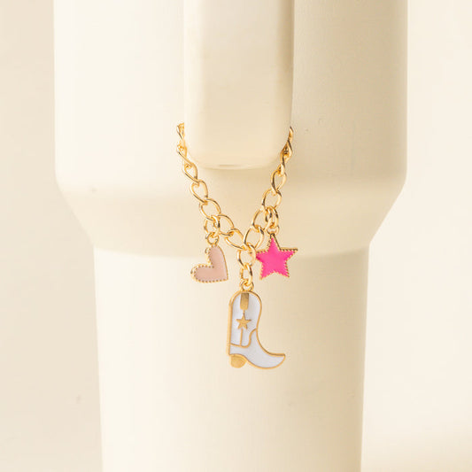 The-darling-effect’s Cowgirl Tumbler Charm—a gold chain bracelet with enamel charms (pink heart, bright pink star, white cowboy boot)—pairs perfectly with your favorite drinkware accessories for a fun, coordinated look.