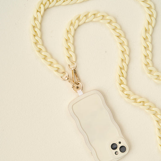 The Darling Effect's Cream Hold the Phone Crossbody Chain features a stylish cream phone case with wavy edges, attached to a chunky cream crossbody chain strap with gold clasps.