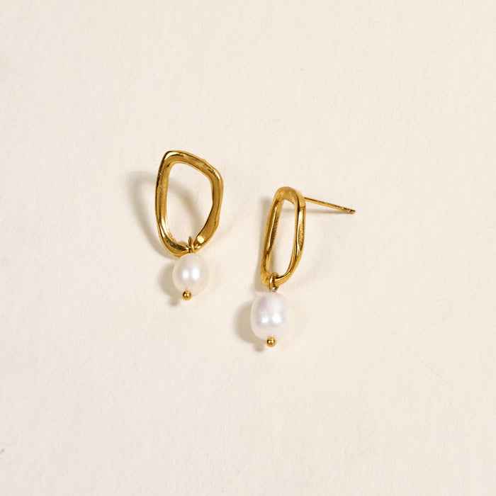 The Darling Effect's Dainty Drift Standout Earrings, featuring irregular shapes and white pearls, shine against a cream background—perfect for special occasions.