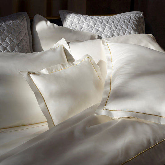 Dalia cream/gold pillowcase sham and duvet cover on a bed
