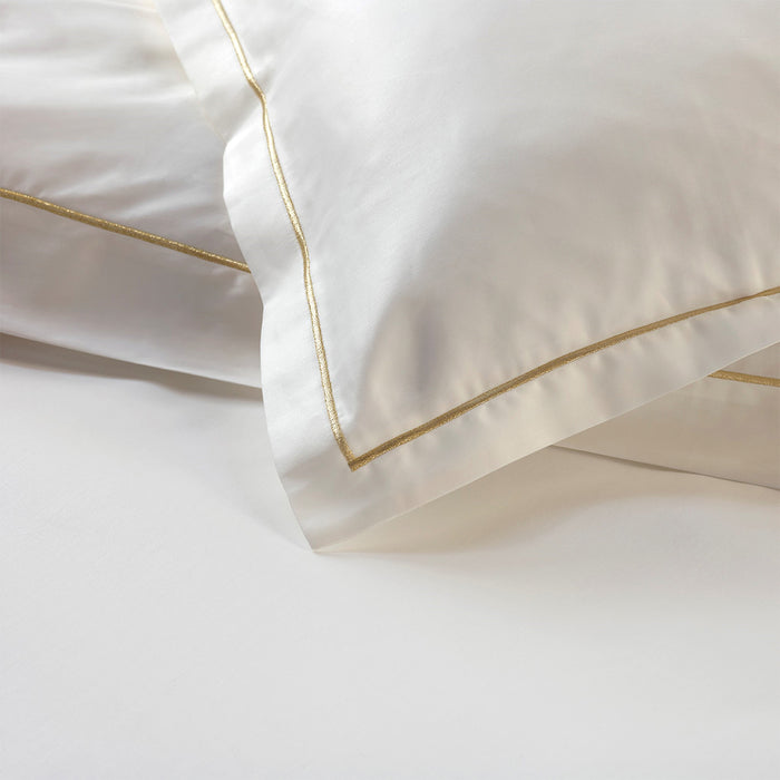 Close-up of Dalia cream/gold pillowcase sham on a white background