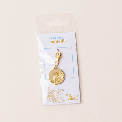 The December Jewelry Birth Flower Charm Gold by the-darling-effect features a gold camellia charm on a clasp, presented on a “December camellia” card—a meaningful accessory for personalized jewelry collections.