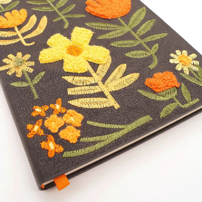 Forager Provisions LTD Denik journal with a black cover featuring textured, chunky folk-style embroidered flowers.