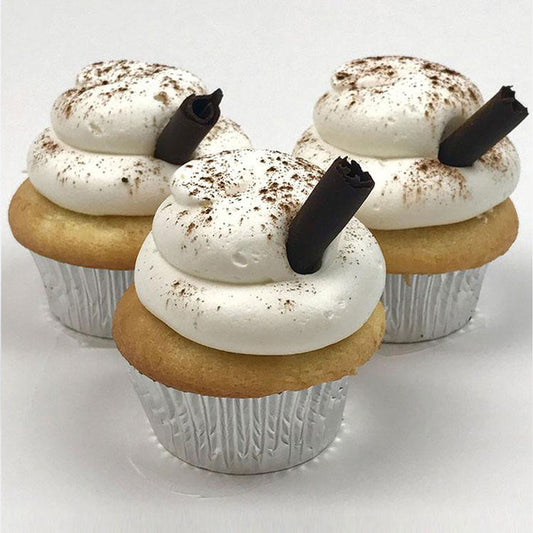 Three Eggnog cupcakes iced with eggnog flavored buttercream, garnished with chocolate cigar and topped with a sprinkle of cinnamon.