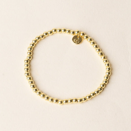 The Ella Beaded Bracelet by the-darling-effect features gold beads and a small round charm inscribed with the letter L—ideal for fans of customizable jewelry.