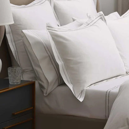 Empire Silver Flat Sheet on a bed with a nightstand and glass in the foreground
