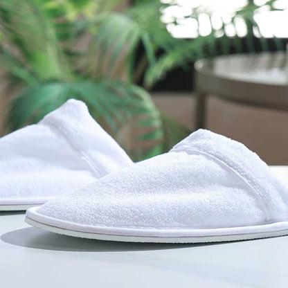 Empire Velour Slippers White / White on a surface with a blurred green background