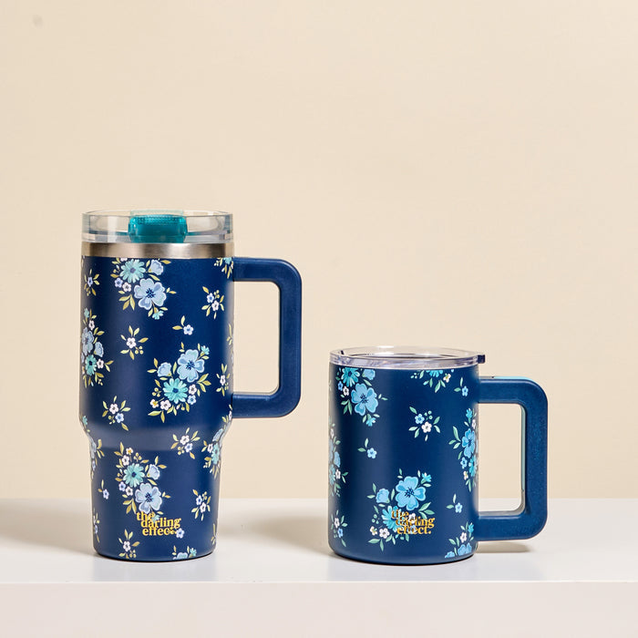 The-darling-effect's Endless Daydream Navy 20 oz Lifestyle Flip Straw Tumbler and a matching mug, both adorned with delicate blue floral patterns, rest on a white surface against a beige background.