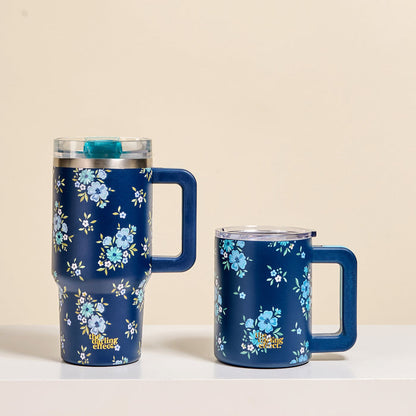 The-darling-effect's Endless Daydream Navy 20 oz Lifestyle Flip Straw Tumbler and a matching mug, both adorned with delicate blue floral patterns, rest on a white surface against a beige background.