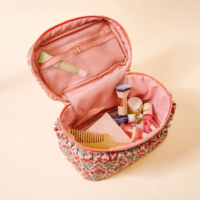 The Darling Effect’s Everbloom Dusty Rose Glam & Go Quilted Cosmetic Bag features a floral pattern and pink striped interior, unzipping to reveal organized makeup items—perfect as a stylish travel companion.