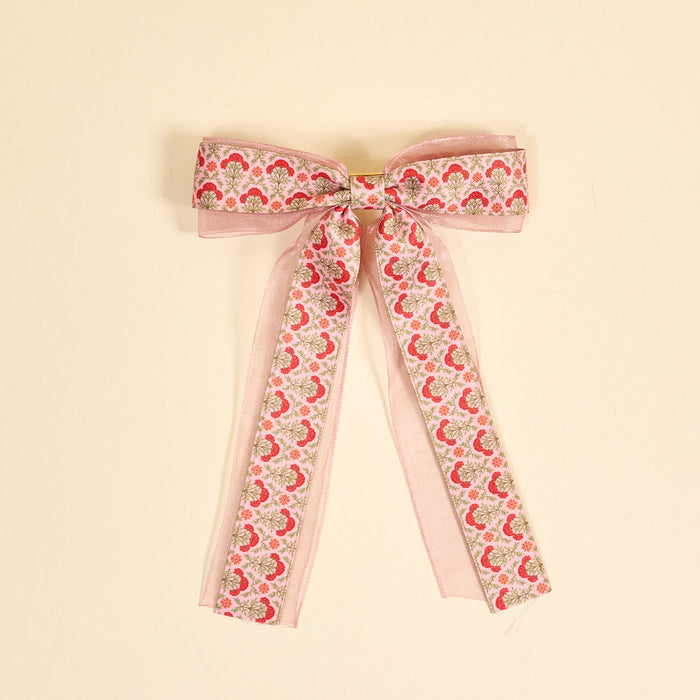 The Darling Effect Everbloom Dusty Rose Lovely Layered Hair Bow features a pink floral print with red and green botanicals, sheer organza edges, and long trailing ribbons—a charming hair accessory for any collection.