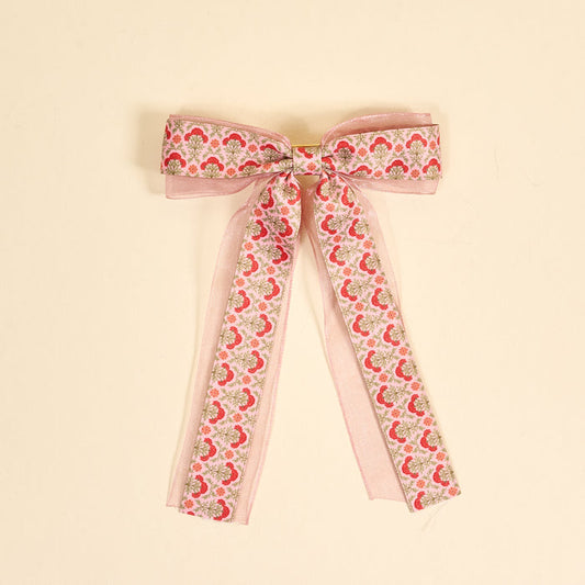 The Darling Effect Everbloom Dusty Rose Lovely Layered Hair Bow features a pink floral print with red and green botanicals, sheer organza edges, and long trailing ribbons—a charming hair accessory for any collection.
