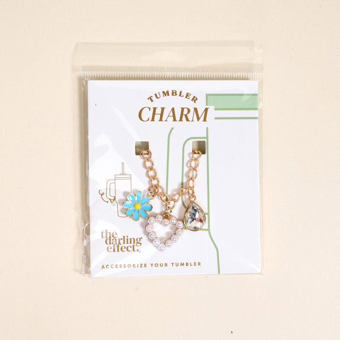 The Darling Effect’s Fairytale Tumbler Charm set features a blue daisy, pearl heart, and crystal teardrop on gold chains—the ideal way to add flair to your favorite tumbler.