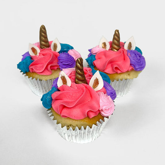 Three Fancy Unicorn Cupcakes with pink, blue, and purple hair, white and gold ears, and golden horns