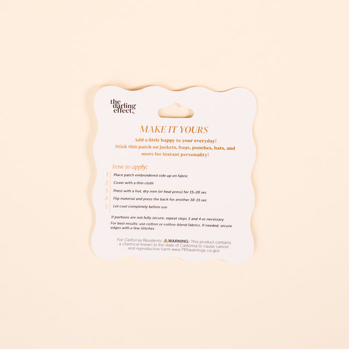 A product instruction card titled MAKE IT YOURS in orange text by The Darling Effect offers directions for applying the Farm Fresh Strawberries Mix & Match Iron-On Patch, so you can customize fabric items. Safety and website info appears at the bottom.