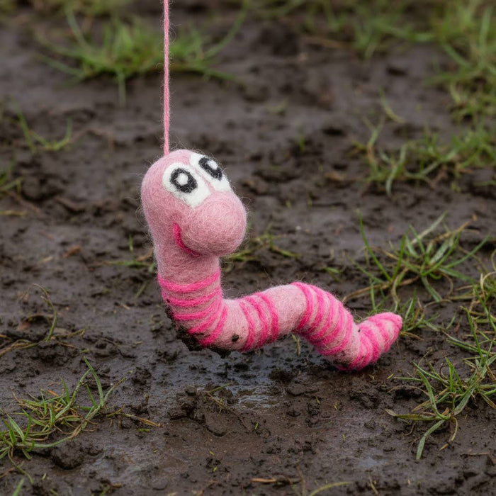 Forager Provisions LTD handmade pink felt worm decoration with striped pattern hanging over muddy ground