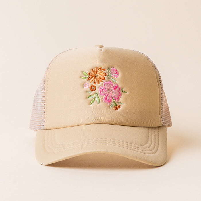 The Flowers Trucker Hat by the-darling-effect is a beige hat with mesh sides, showcasing an embroidered floral design of pink, orange, and yellow flowers with green leaves on the front.