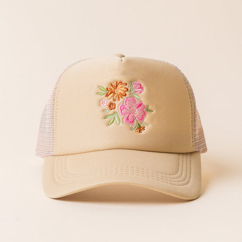The Flowers Trucker Hat by the-darling-effect is a beige hat with mesh sides, showcasing an embroidered floral design of pink, orange, and yellow flowers with green leaves on the front.