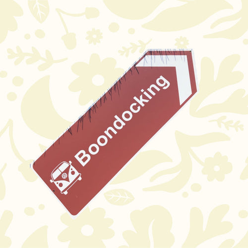 Directional sign pointing to 'Boondocking' with a vintage van icon on a grass background