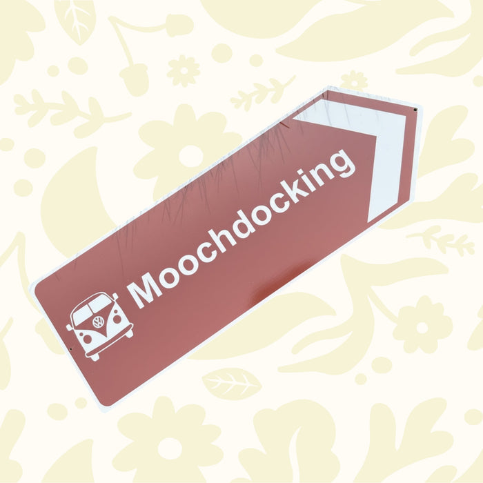 Directional sign pointing to 'Mooch docking' with a Volkswagen van icon on a grass background.