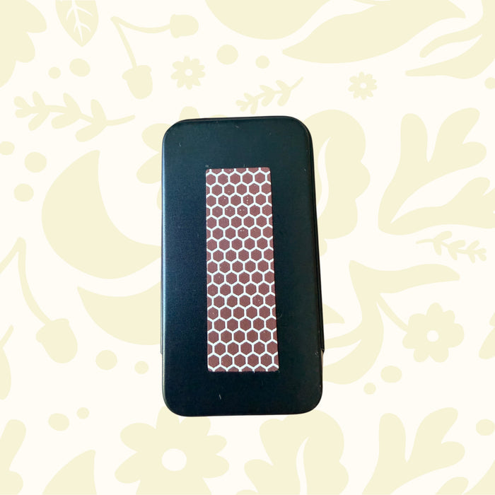 Forager Provisions LTD metal stash tin featuring a brown honeycomb match striker surface on the back