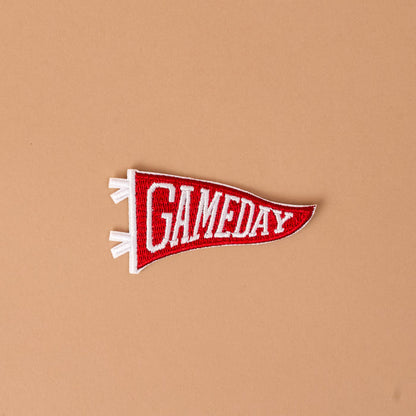 A burgundy and white embroidered "Gameday" patch from The Darling Effect, shown on a plain light brown background—perfect for fans of colorful designs who want to customize their look with this unique Mix & Match iron-on patch.