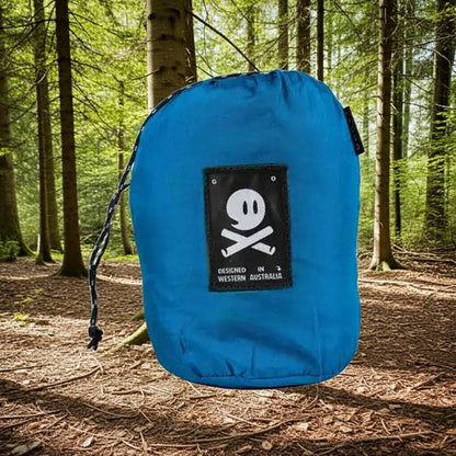 Forager Provisions LTD Ghost Outdoors peacock blue packable travel hammock in its compact storage bag in a forest.