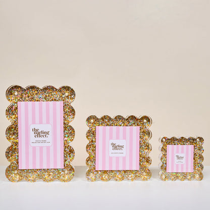The Darling Effect Gold Glitter Little Moments Acrylic Picture Frame features scalloped edges, pink and white striped inserts, and a secure magnetic closure for easy display and access.