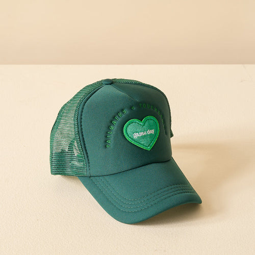 The Darling Effect Green Game Day Trucker Hat features a mesh back, heart patch with "game day," and "tailgates & touchdowns" embroidered on the crown—perfect for showing your team spirit.