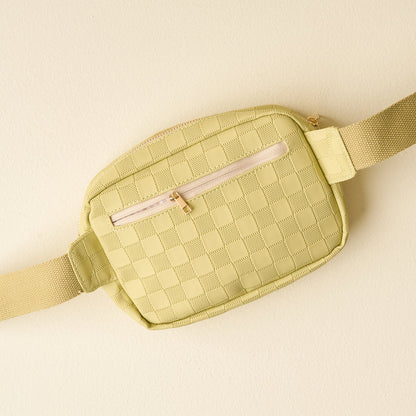 The Darling Effect's Green Urban Check Belt Bag features vegan leather, a front zipper pocket, and an adjustable strap, shown on a matching pale green background.