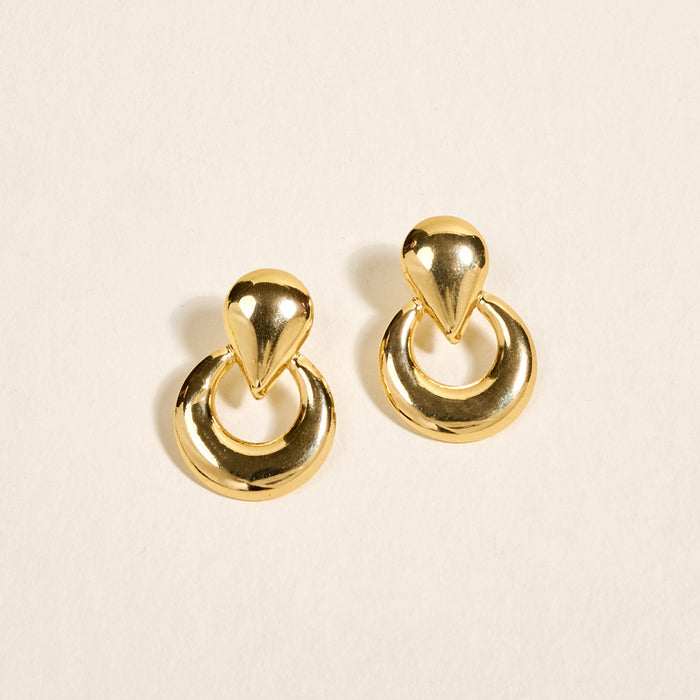 The Darling Effect’s Heirloom Standout Earrings feature a teardrop-shaped stud with a circular hoop below, showcased on a light neutral background—ideal for those who love statement jewelry.