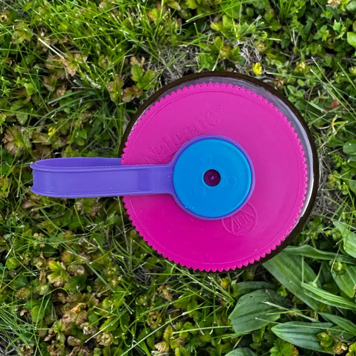 Hey Bear Outdoors “Respect The Locals” 32oz Nalgene bottle with purple handle on green grass, perfect for hiking or camping.