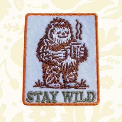 Forager Provisions LTD embroidered iron-on patch featuring a brown Bigfoot drinking coffee with Stay Wild text.
