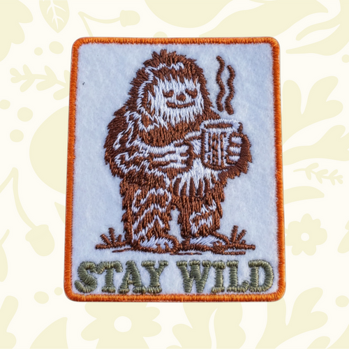 Forager Provisions LTD embroidered iron-on patch featuring a brown Bigfoot drinking coffee with Stay Wild text.