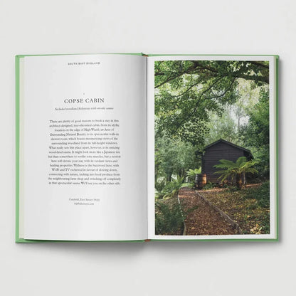 British Cabins and Hideaways book by Hoxton Mini Press features a dark UK cabin surrounded by lush green forest woods.