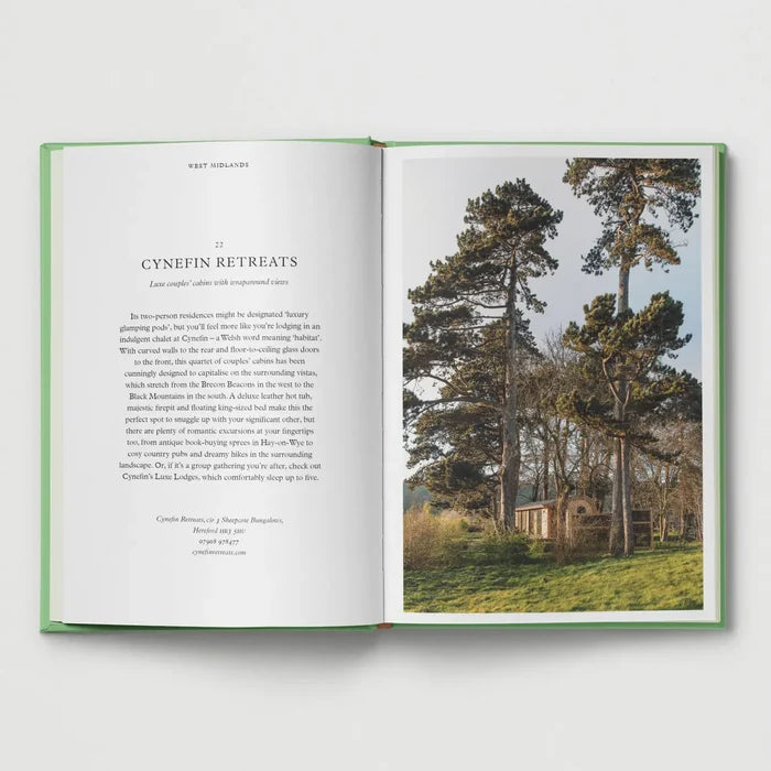 Open book featuring “British Cabins and Hideaways” by Hoxton Mini Press, pine tree cabin photo on right page. Cozy UK travel.