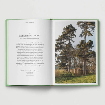 Open book featuring “British Cabins and Hideaways” by Hoxton Mini Press, pine tree cabin photo on right page. Cozy UK travel.