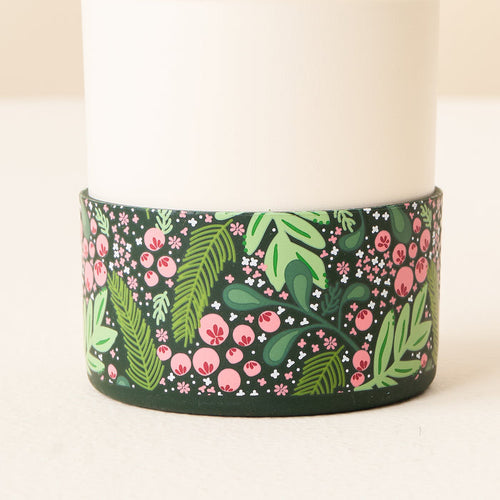 A close-up of the bottom of a white tumbler with a green and pink floral pattern, featuring The Darling Effect's Jolly Sprig Green Tumbler Silicone Boot for added protection.