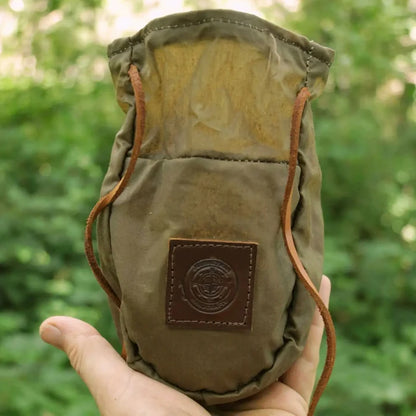 Hand holding khaki green Journeyman Craft waxed canvas coffee pouch, perfect for camping, hiking, and outdoor adventures.