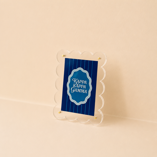 The Darling Effect Kappa Kappa Gamma Mini Acrylic Picture Frame Magnet features a scalloped-edge clear frame holding a blue sign with white text, displayed on a beige background.