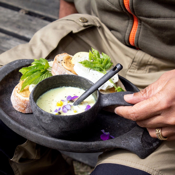 Person carrying tray with soup, bread, and black Kupilka Spork 225 Long Utensil—perfect mealtime convenience and stylish dining.