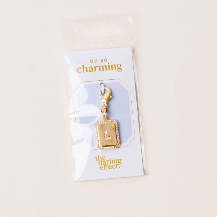 The-darling-effect L Jewelry Charm Initial Letter Gold features a gold-plated brass charm with rhinestone border, lobster clasp, and comes attached to an OH SO charming packaging card in a clear plastic bag.
