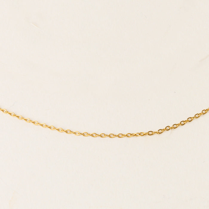 The Leona Charm Necklace Chain by the-darling-effect, featuring a distinctive gold design, is showcased on a simple light beige background.