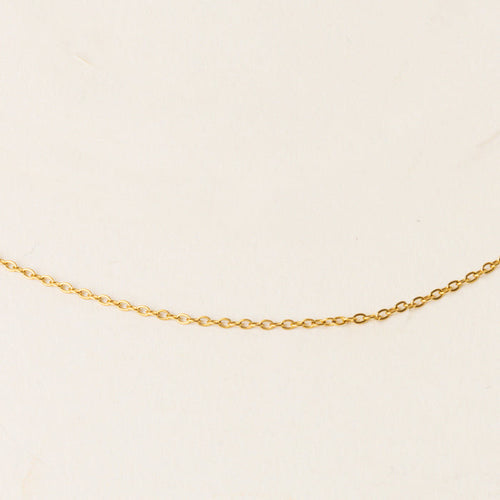 The Leona Charm Necklace Chain by the-darling-effect, featuring a distinctive gold design, is showcased on a simple light beige background.