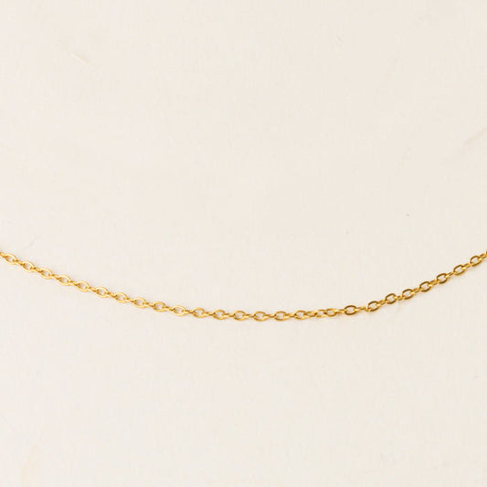 The Leona Charm Necklace Chain by the-darling-effect, featuring a distinctive gold design, is showcased on a simple light beige background.
