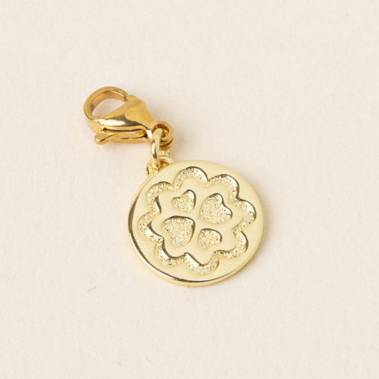 The-darling-effect Loving Jewelry Trait Charm Gold features a circular pendant engraved with a four-leaf clover, symbolizing strength and confidence, and comes with a lobster clasp, displayed on a light background.