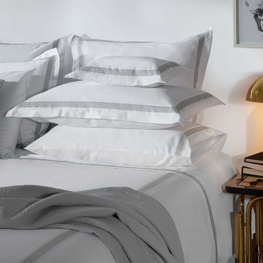 Stack of Luis-White-Grey pillowcases on a bed in a bedroom setting.