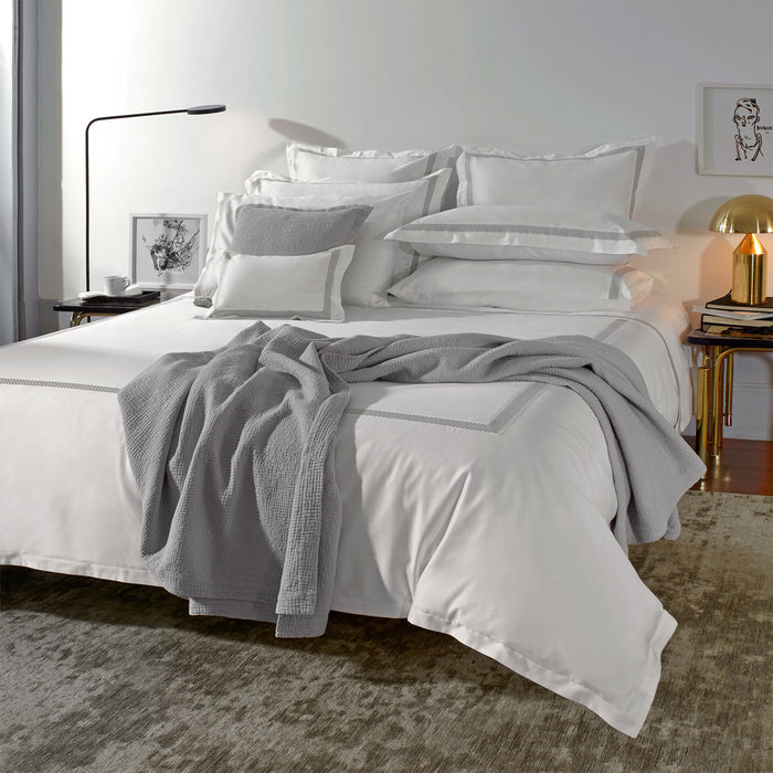 Neatly made bed with Luis-White-Grey duvet cover and pillowcase sham in a bedroom setting.
