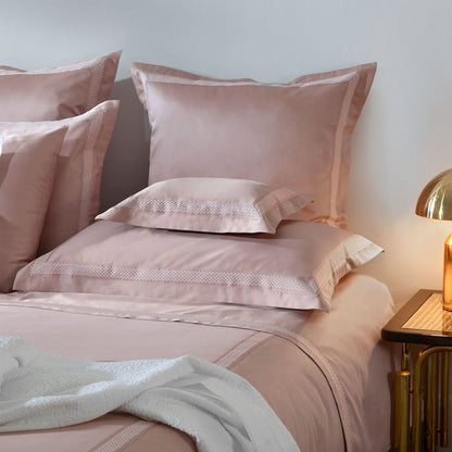 Luis-CharmPink duvet cover and pillowcase sham on a bed in a softly lit room.