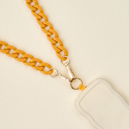 The Darling Effect’s Mustard Hold the Phone Crossbody Chain features a chunky yellow chain, gold clasps, and a cream holder—combining style and function as a chic hands-free phone accessory.